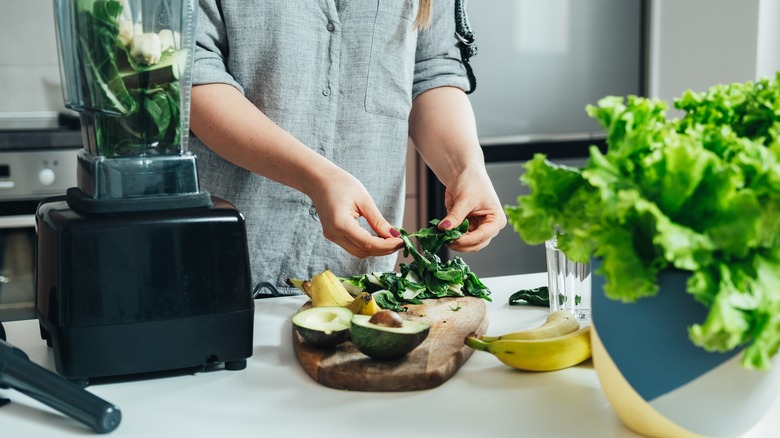 A woman prepares spinach for a smoothie