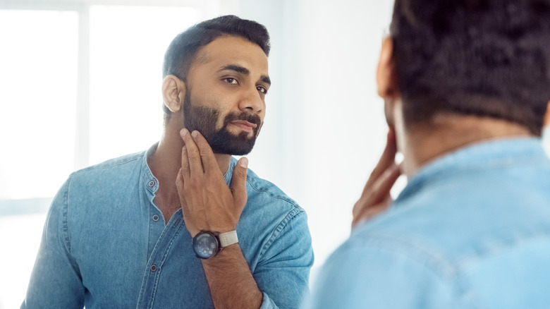 Man examining face in mirror