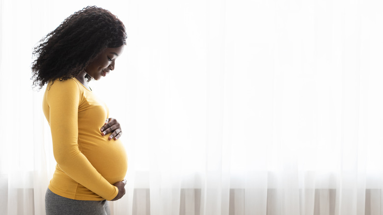 Pregnant woman looking down holding stomach