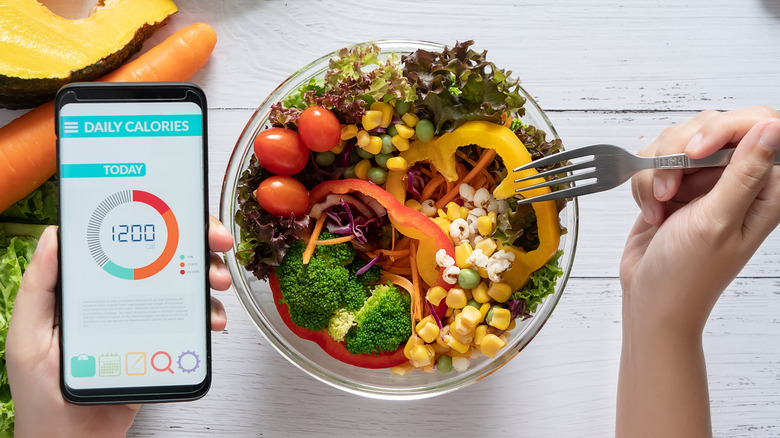 Woman eating salad while using an app to track calories