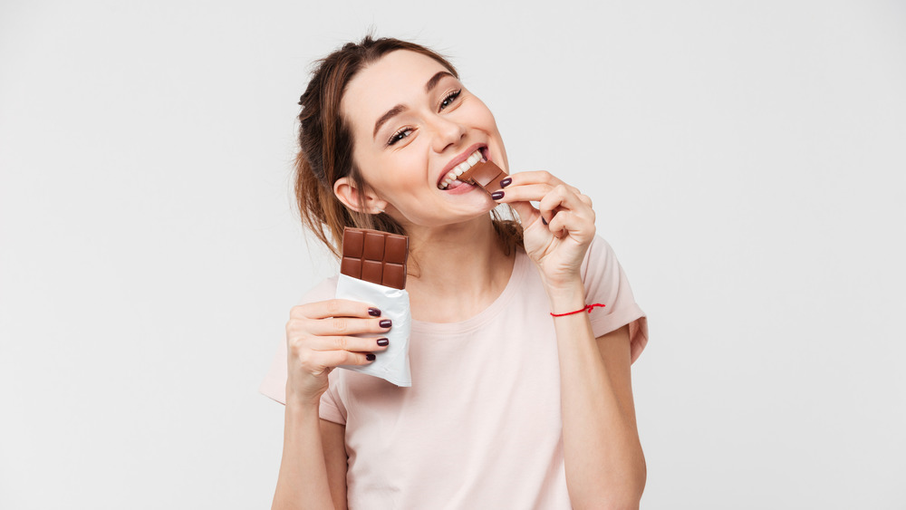 happy woman eating a bar of chocolate 