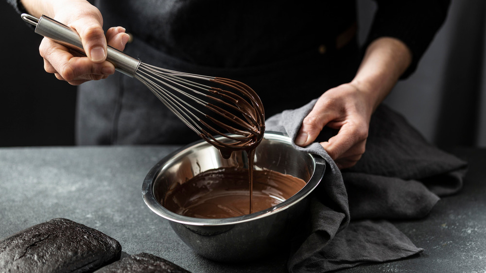 woman mixing chocolate batter in a metal bowl 