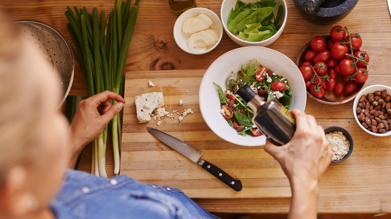 overhead view of woman making a salad with dressing