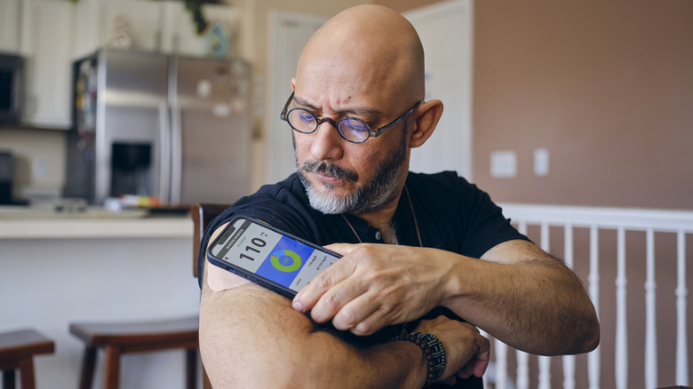 adult man checking his blood sugar using an app