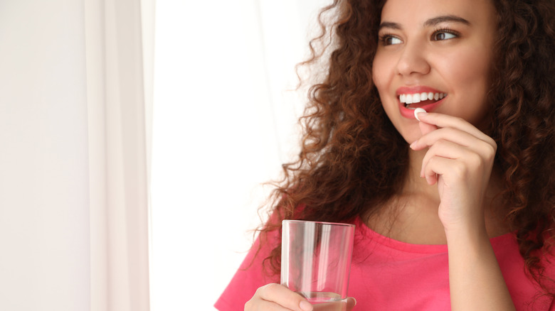 Woman taking Benadryl with a glass of water