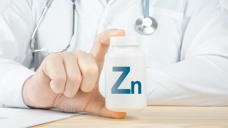 A doctor holds a bottle of zinc supplements