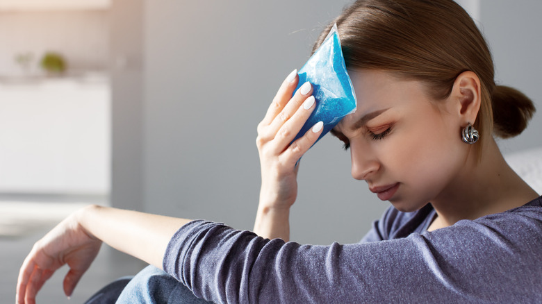 Woman treating headache with ice pack