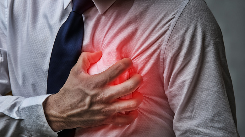 man grasping chest with hand, having heart attack