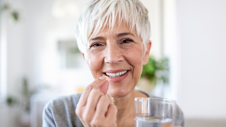 woman taking medicine with glass of water