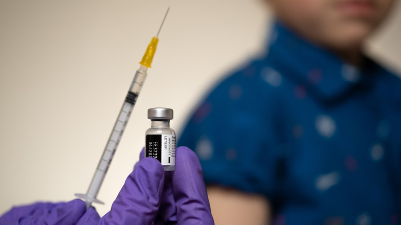 Nurse's hands hold needle and vaccine vial