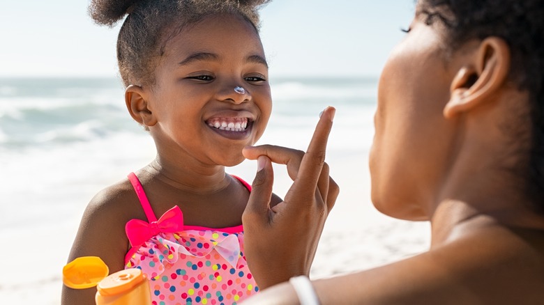 mother applying sunscreen to kid