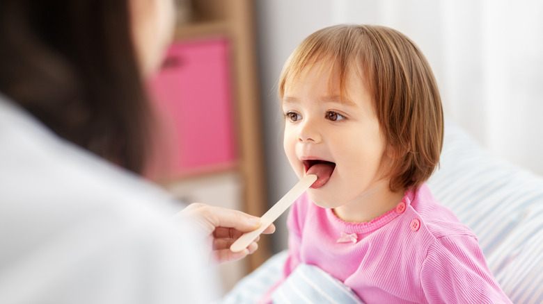 Using tongue depressor on child