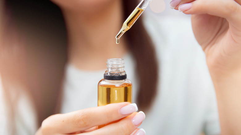 Woman holding a bottle of oil and dropper