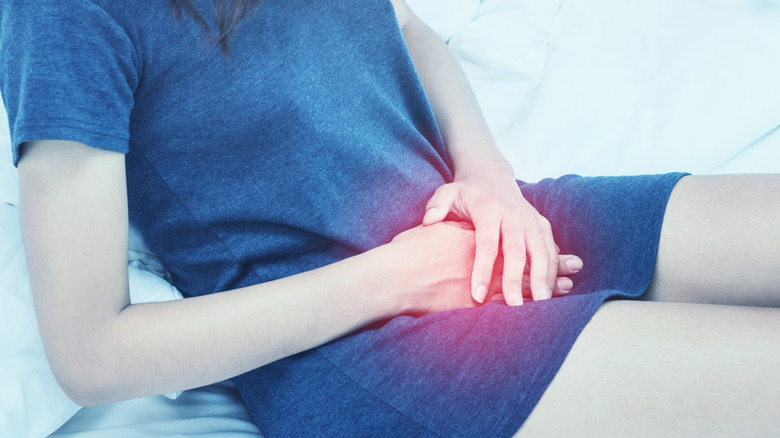 woman with bladder pain sitting on bed