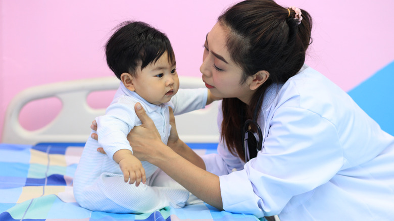 kneeling doctor holding seated baby