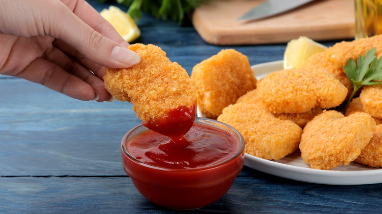 Girl dunks chicken nuggets in sauce