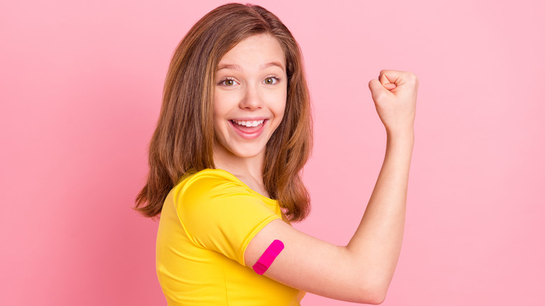teenage girl flexing bicep with pink bandaid