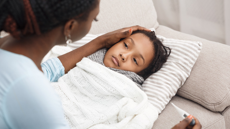 sick child with parent taking temperature