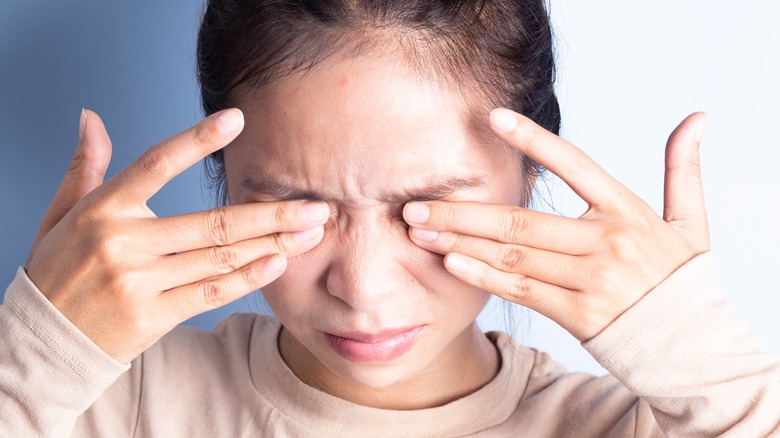 young woman rubbing eyes