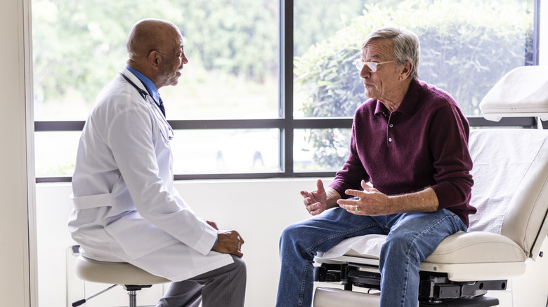 An older man talking with his doctor in an exam room