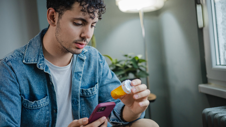 man reading label on pill bottle