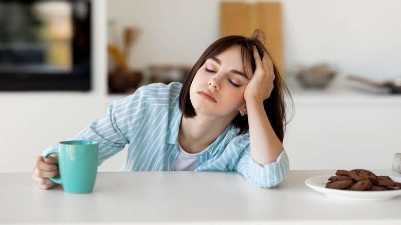 Tired woman sitting in kitchen with mug