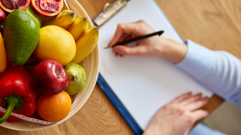 Woman writing meal plan on clipboard