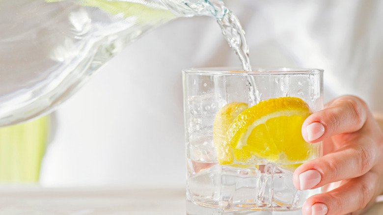 Person pouring water with lemon