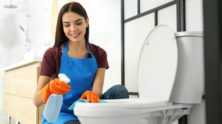 Smiling woman cleaning toilet