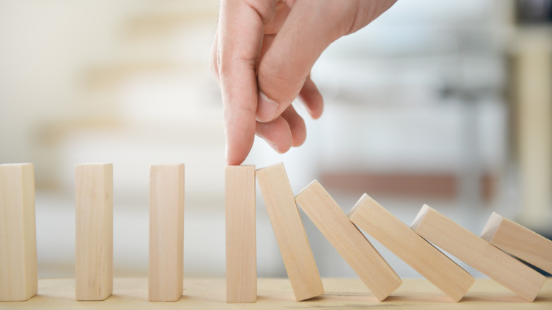 Hand keeping wooden block from falling