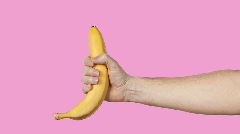 Hand holding a banana symbolizing a penis