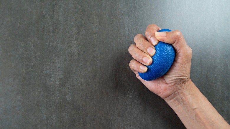 Man's hand squeezing blue stress ball