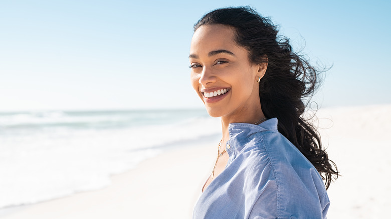 woman smiling while standing by the seashore