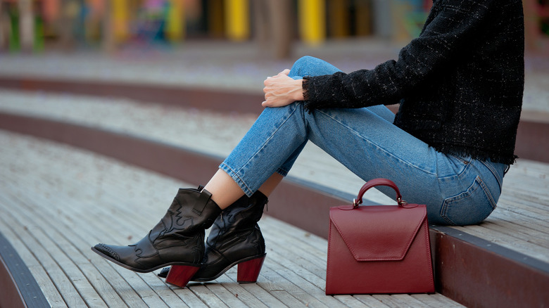 A woman in skinny jeans, black boots, and a black top