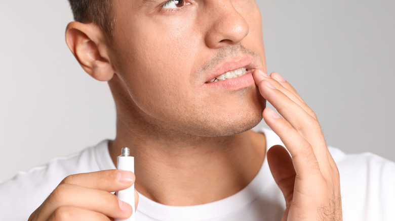 Man applying lip ointment with finger