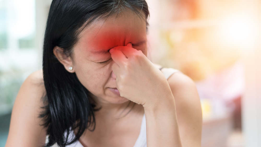 Woman pinching bridge of nose with sinus pain