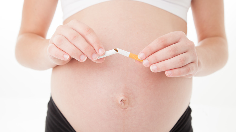 pregnant woman breaking cigarette