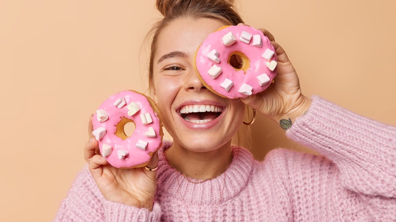 Woman smiling while holding two donuts