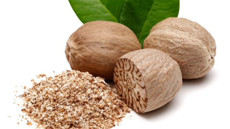 whole and grated nutmeg on white background