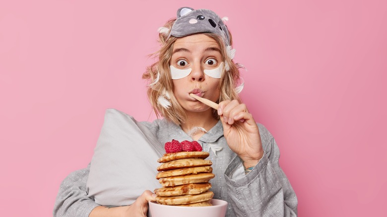 woman brushing teeth with breakfast out of bed