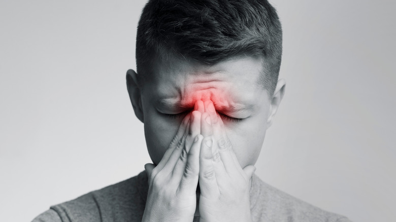 man holding tissue to nose