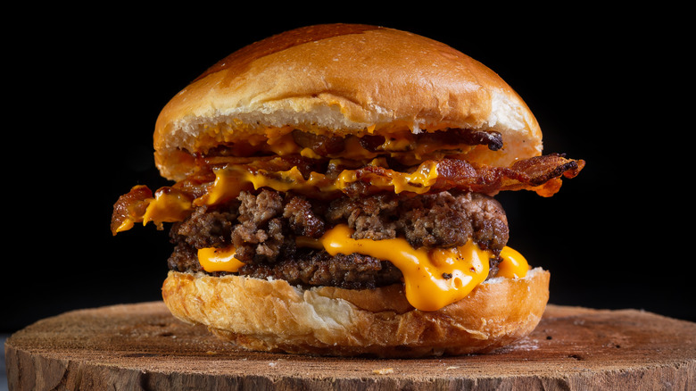 a bacon cheeseburger on a wooden surface