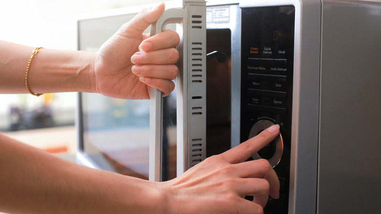 close up of hands using a microwave