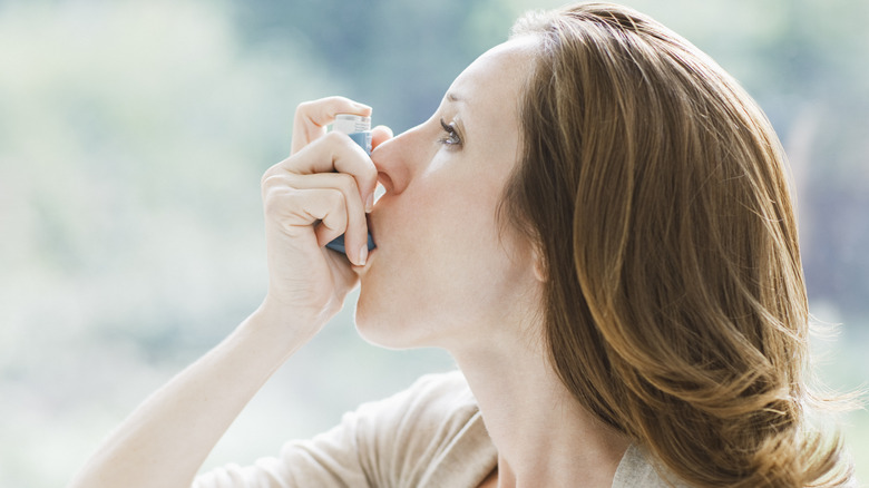 Woman taking rescue inhaler to help with asthma