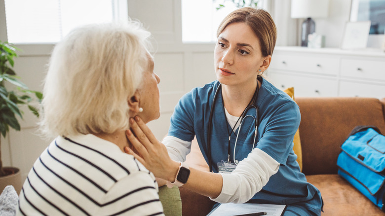 Woman having her thyroid examined by a female doctor