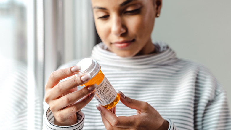 Sad-looking woman holding a pill bottle