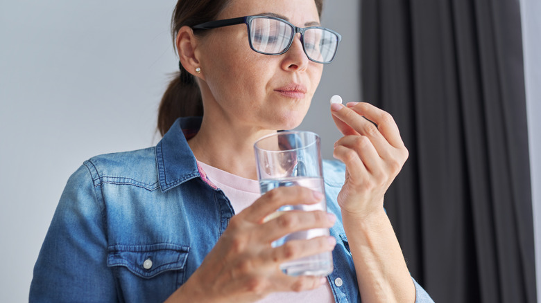 Woman holding pill with glass of water