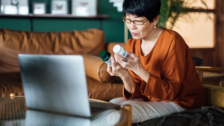 Woman looking at her medication bottles