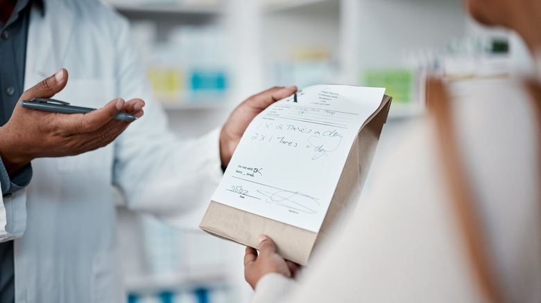 Pharmacist handing prescription meds to client