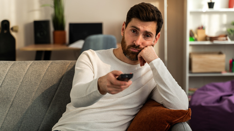 A man sitting on the couch idly watching television